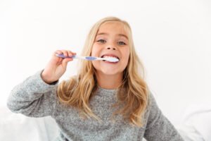 A kid with a toothbrush demonstrating good dental habits as part of a pediatric dentist toothbrush recommendation in Beverly Hills.