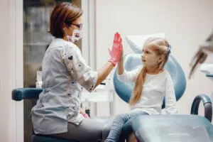 Dentist in Beverly Hills, gives a high-five to a kid, helping to alleviate any fear of dentist in children.