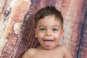 A baby boy with his tongue slightly out, epresent the subtle indicators of tongue ties in infants.