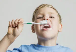 A child brushes their teeth with a toothbrush, relevant to Fluoride & Baby Toothbrushes in Beverly Hills.