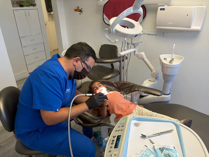 Dr. Sepehr Nassiripour carefully working on a child's teeth during a dental filling procedure